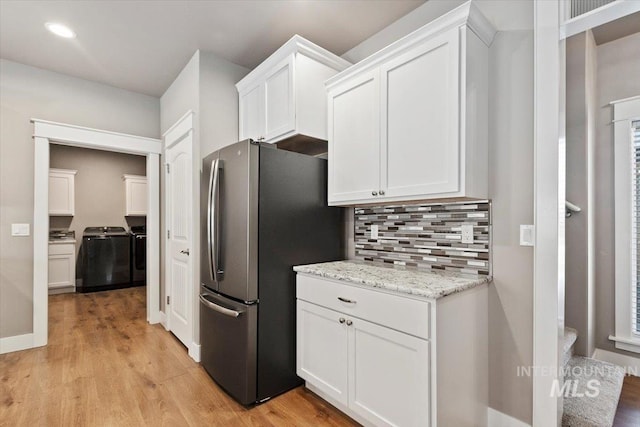 kitchen featuring white cabinetry, separate washer and dryer, light wood-type flooring, stainless steel fridge, and decorative backsplash