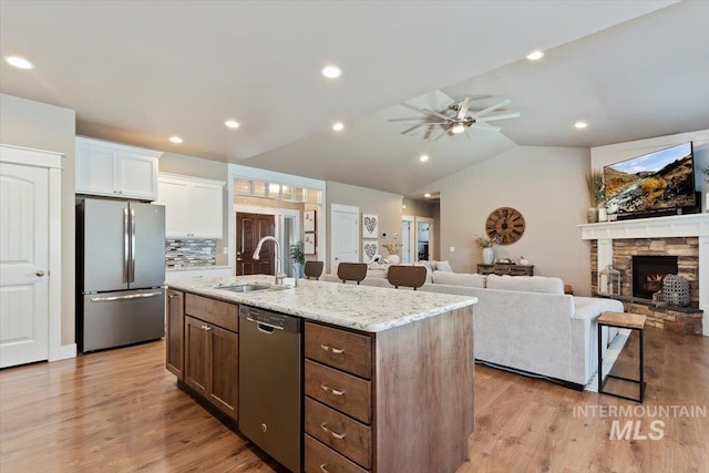 kitchen featuring sink, white cabinetry, vaulted ceiling, appliances with stainless steel finishes, and an island with sink