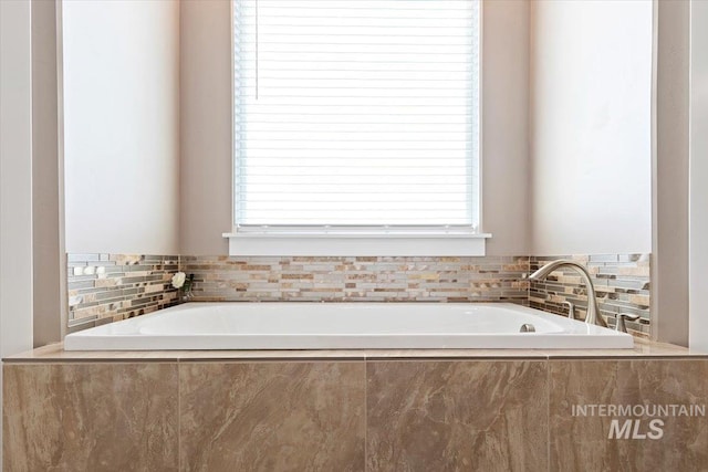 bathroom with a relaxing tiled tub and plenty of natural light