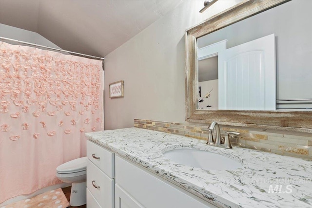 bathroom featuring lofted ceiling, vanity, toilet, and decorative backsplash