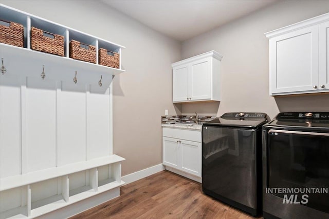 clothes washing area featuring sink, cabinets, hardwood / wood-style flooring, and washer and dryer