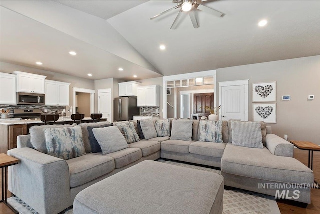 living room featuring ceiling fan, lofted ceiling, and light wood-type flooring