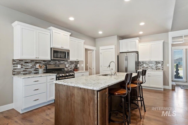 kitchen featuring appliances with stainless steel finishes, a kitchen island with sink, and white cabinets