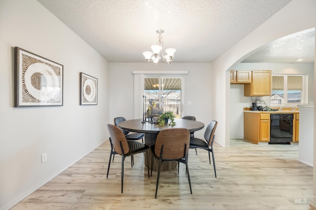 dining space with a textured ceiling, a chandelier, and light hardwood / wood-style flooring