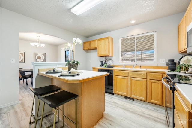 kitchen with a textured ceiling, light hardwood / wood-style flooring, a chandelier, pendant lighting, and stainless steel appliances