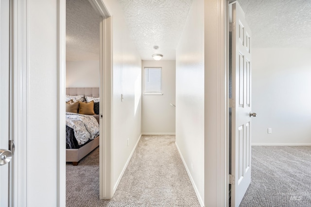 hall with a textured ceiling and light carpet