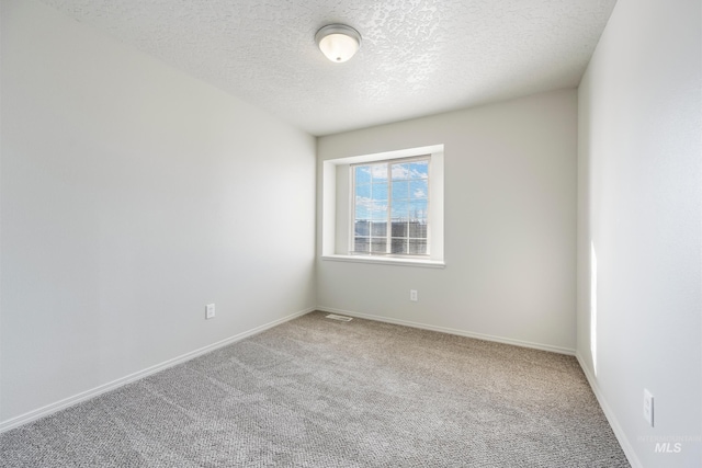 carpeted empty room featuring a textured ceiling