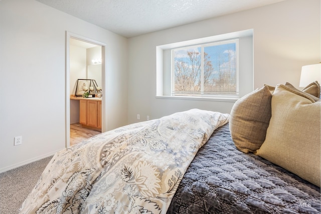 bedroom with ensuite bath, a textured ceiling, and carpet