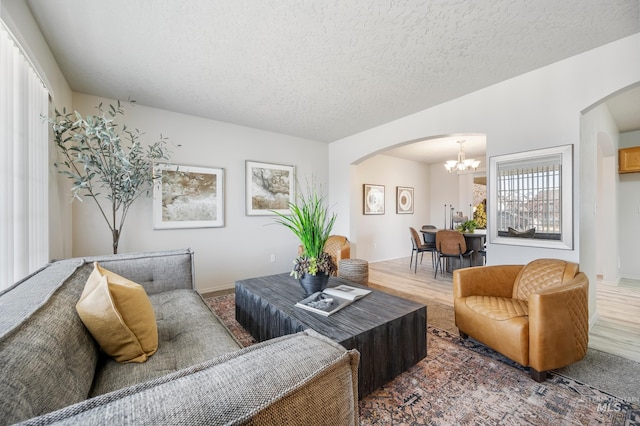 living room featuring an inviting chandelier, hardwood / wood-style floors, and a textured ceiling