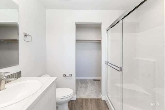 4352 N Glassford Ave, Meridian, ID 83646 - full bathroom featuring a walk in closet, toilet, a stall shower, wood finished floors, and vanity
