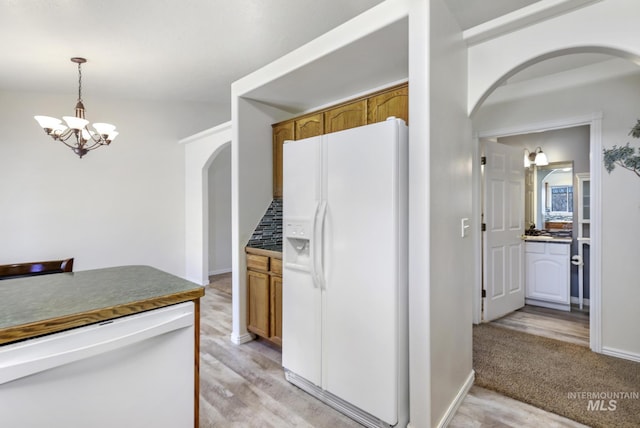 2563 Paintbrush Dr, Twin Falls, ID 83301 - kitchen with white refrigerator with ice dispenser, arched walkways, brown cabinetry, a chandelier, and pendant lighting