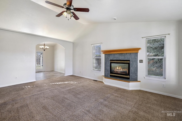 2563 Paintbrush Dr, Twin Falls, ID 83301 - unfurnished living room featuring carpet flooring, plenty of natural light, a tiled fireplace, arched walkways, and vaulted ceiling