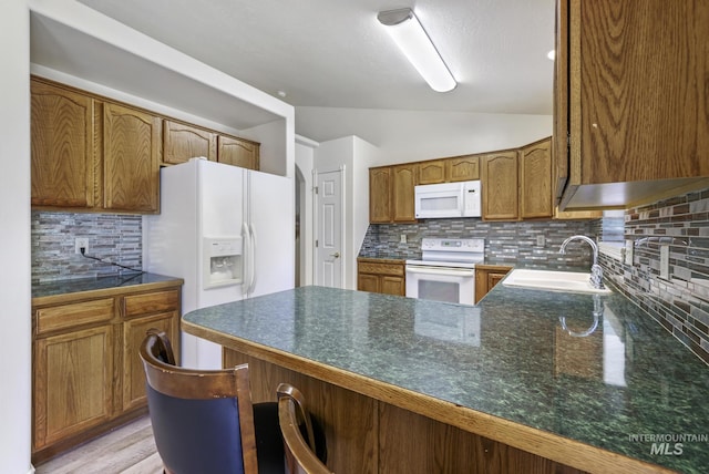 2563 Paintbrush Dr, Twin Falls, ID 83301 - kitchen with white appliances, a peninsula, tasteful backsplash, lofted ceiling, and dark countertops