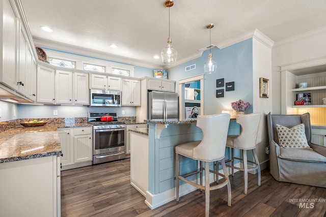 998 E Shadow Creek Ln, Eagle, ID 83616 - kitchen featuring stainless steel appliances, ornamental molding, dark wood-type flooring, a kitchen breakfast bar, and white cabinetry