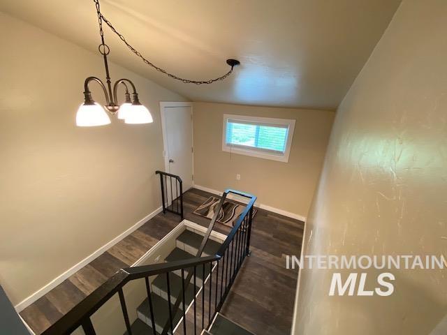 staircase with baseboards, wood finished floors, vaulted ceiling, and a chandelier
