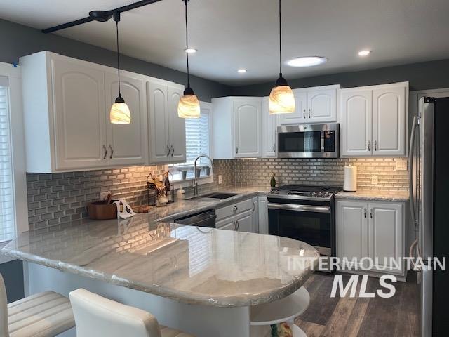 kitchen with stainless steel appliances, a peninsula, white cabinetry, a sink, and recessed lighting