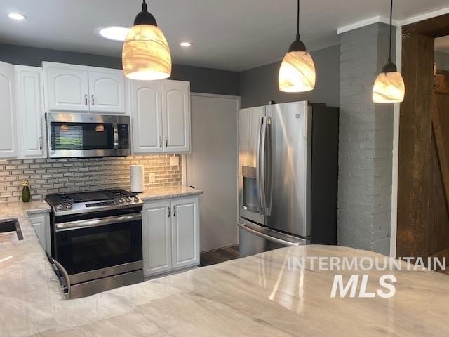 kitchen with stainless steel appliances, decorative backsplash, white cabinets, light stone countertops, and decorative light fixtures