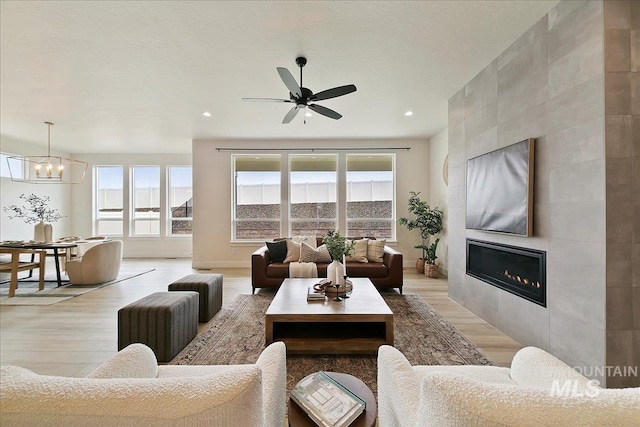 6356 S Cubola Way, Meridian, ID 83642 - living area featuring light wood finished floors, a chandelier, a tiled fireplace, a ceiling fan, and recessed lighting
