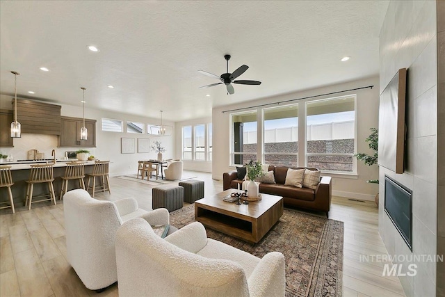 6356 S Cubola Way, Meridian, ID 83642 - living room with light wood-style floors, recessed lighting, a ceiling fan, baseboards, and a glass covered fireplace
