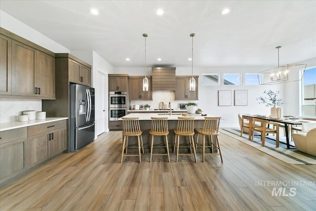 6356 S Cubola Way, Meridian, ID 83642 - kitchen featuring appliances with stainless steel finishes, light wood finished floors, light countertops, a breakfast bar, and recessed lighting
