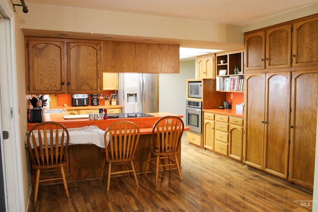 kitchen featuring appliances with stainless steel finishes, hardwood / wood-style flooring, and a breakfast bar area