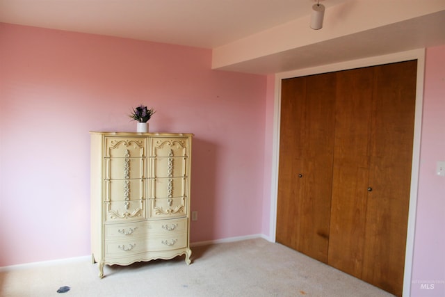 unfurnished bedroom with light colored carpet and a closet