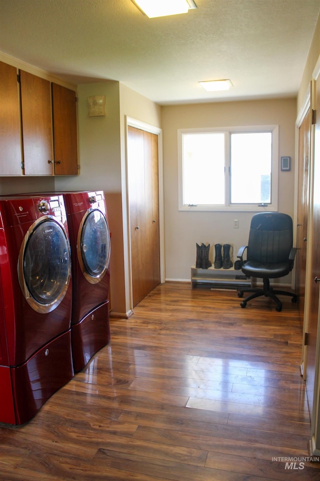 laundry area featuring a textured ceiling, dark hardwood / wood-style flooring, cabinets, and washing machine and dryer