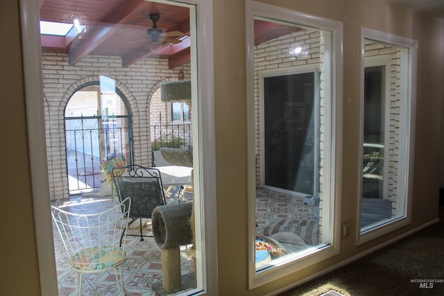 interior details featuring ceiling fan, beamed ceiling, and a skylight