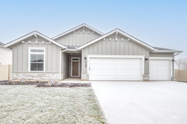 view of front of property featuring a garage, stone siding, board and batten siding, and concrete driveway