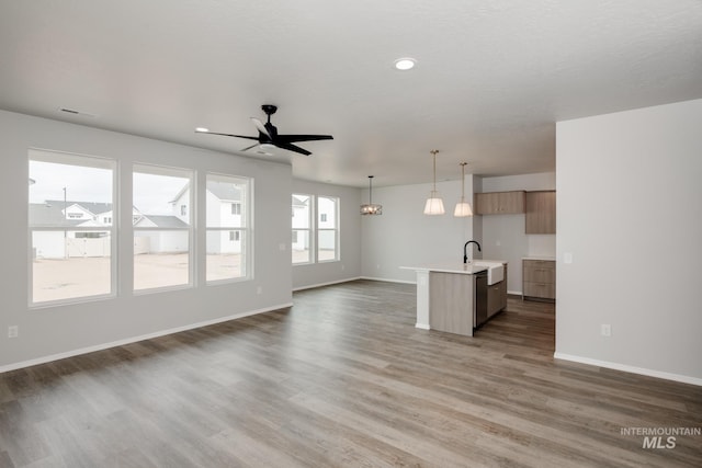 unfurnished living room featuring dark wood-style flooring, recessed lighting, a ceiling fan, a sink, and baseboards