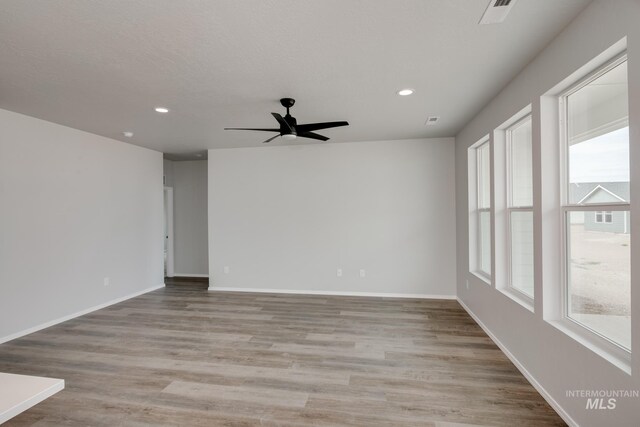 empty room with light wood-style flooring, baseboards, and recessed lighting