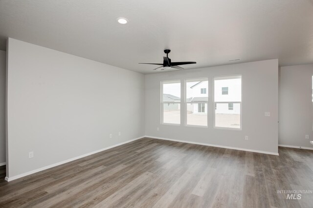 unfurnished room featuring ceiling fan, wood finished floors, and baseboards