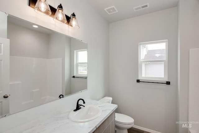 bathroom featuring toilet, walk in shower, vanity, and visible vents