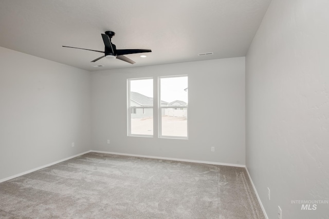 spare room featuring visible vents, ceiling fan, light carpet, and baseboards