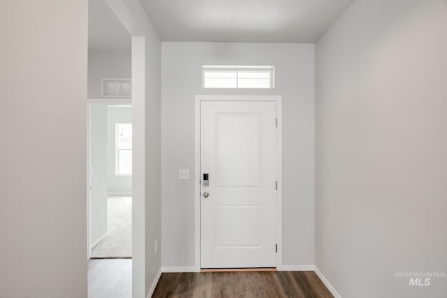 foyer entrance with baseboards, visible vents, and dark wood-style flooring