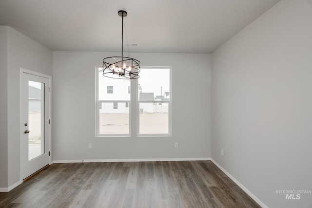 unfurnished dining area with plenty of natural light, wood finished floors, and an inviting chandelier