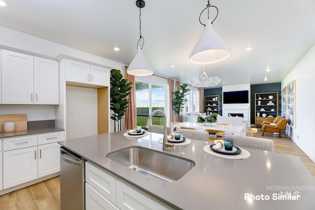 kitchen featuring sink, pendant lighting, stainless steel dishwasher, and light wood-type flooring