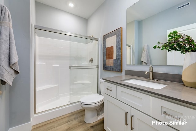 bathroom with toilet, vanity, a shower with shower door, and hardwood / wood-style flooring