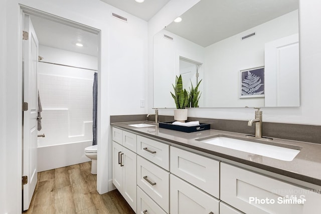 full bathroom with hardwood / wood-style floors, vanity, toilet, and shower / bathtub combination with curtain