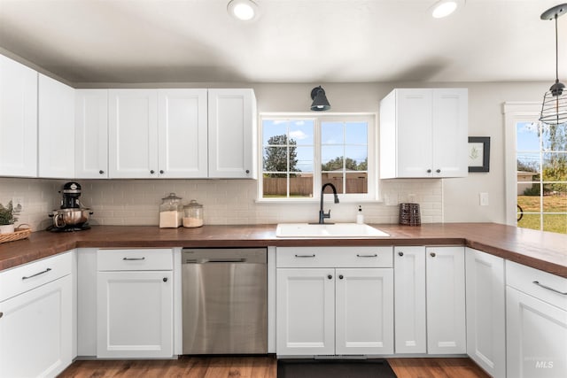 kitchen featuring stainless steel dishwasher, a sink, butcher block counters, tasteful backsplash, and wood finished floors