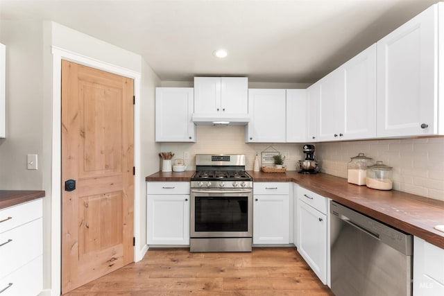 kitchen featuring stainless steel appliances, wooden counters, decorative backsplash, under cabinet range hood, and recessed lighting
