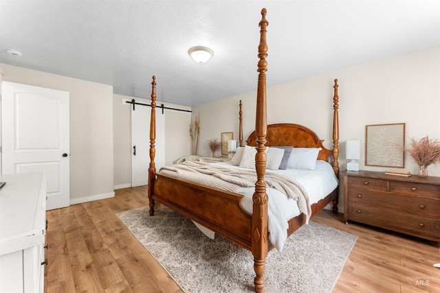 bedroom featuring light wood-style floors, baseboards, and a barn door