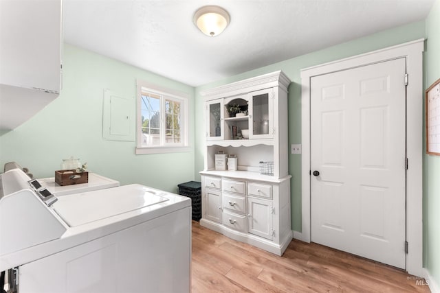 clothes washing area with separate washer and dryer and light wood-type flooring