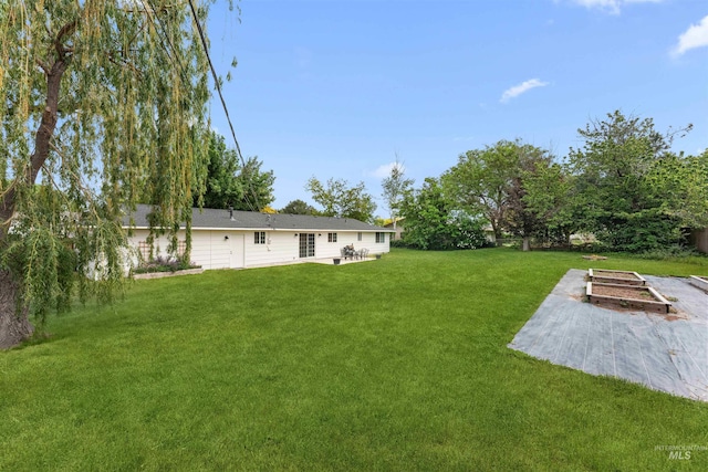 view of green lawn with a garden and a patio