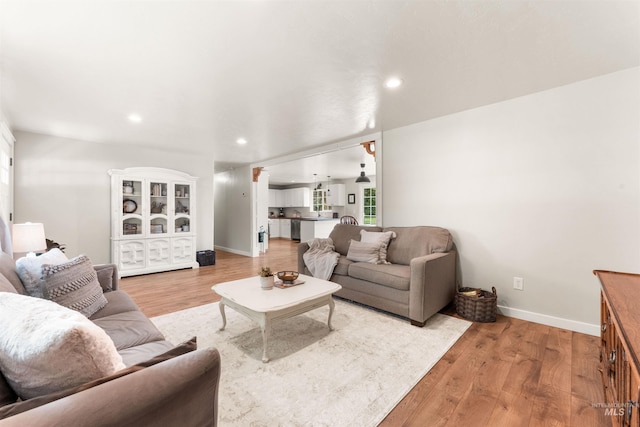 living room featuring baseboards, recessed lighting, wood finished floors, and plenty of natural light
