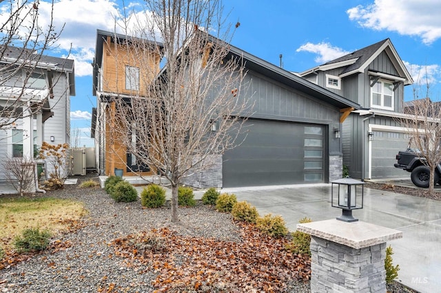 view of front facade featuring board and batten siding, an attached garage, driveway, and fence