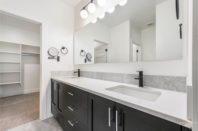 bathroom featuring double vanity, visible vents, a spacious closet, and a sink