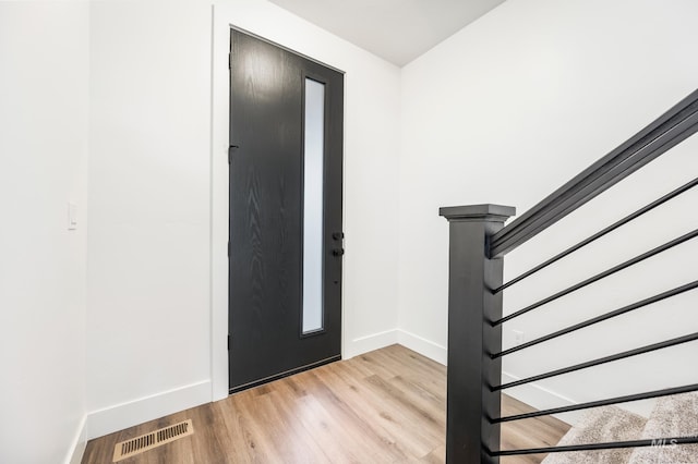 entrance foyer featuring light wood finished floors, visible vents, stairway, and baseboards