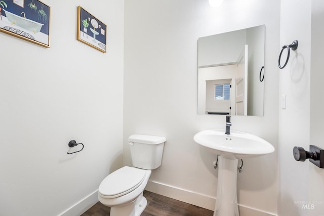 bathroom with toilet, baseboards, and wood finished floors