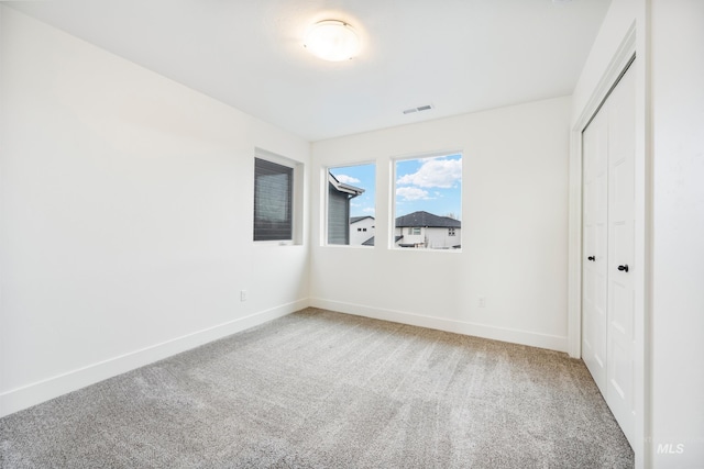 unfurnished bedroom with visible vents, carpet floors, baseboards, and a closet